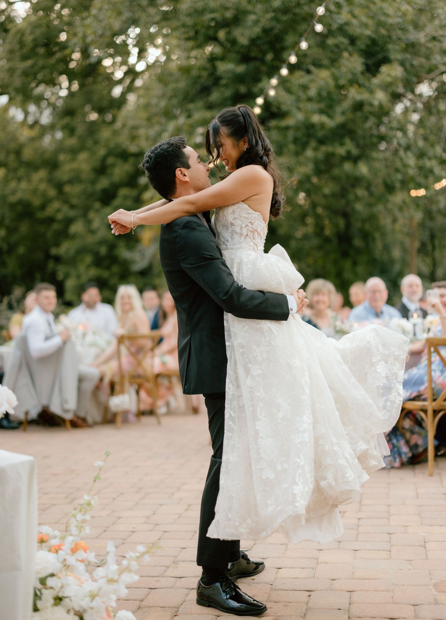 A sequence of wedding dance photos showing playful dips and spins on a stone patio during an outdoor reception.