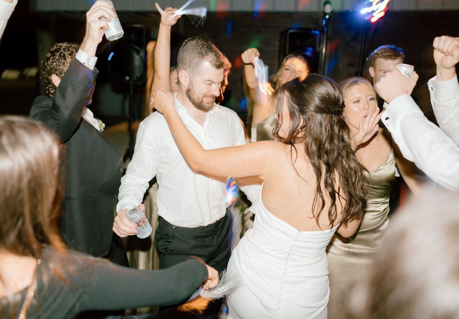 People dancing and celebrating at a lively wedding reception party with dim lighting and festive atmosphere during a wedding reception.