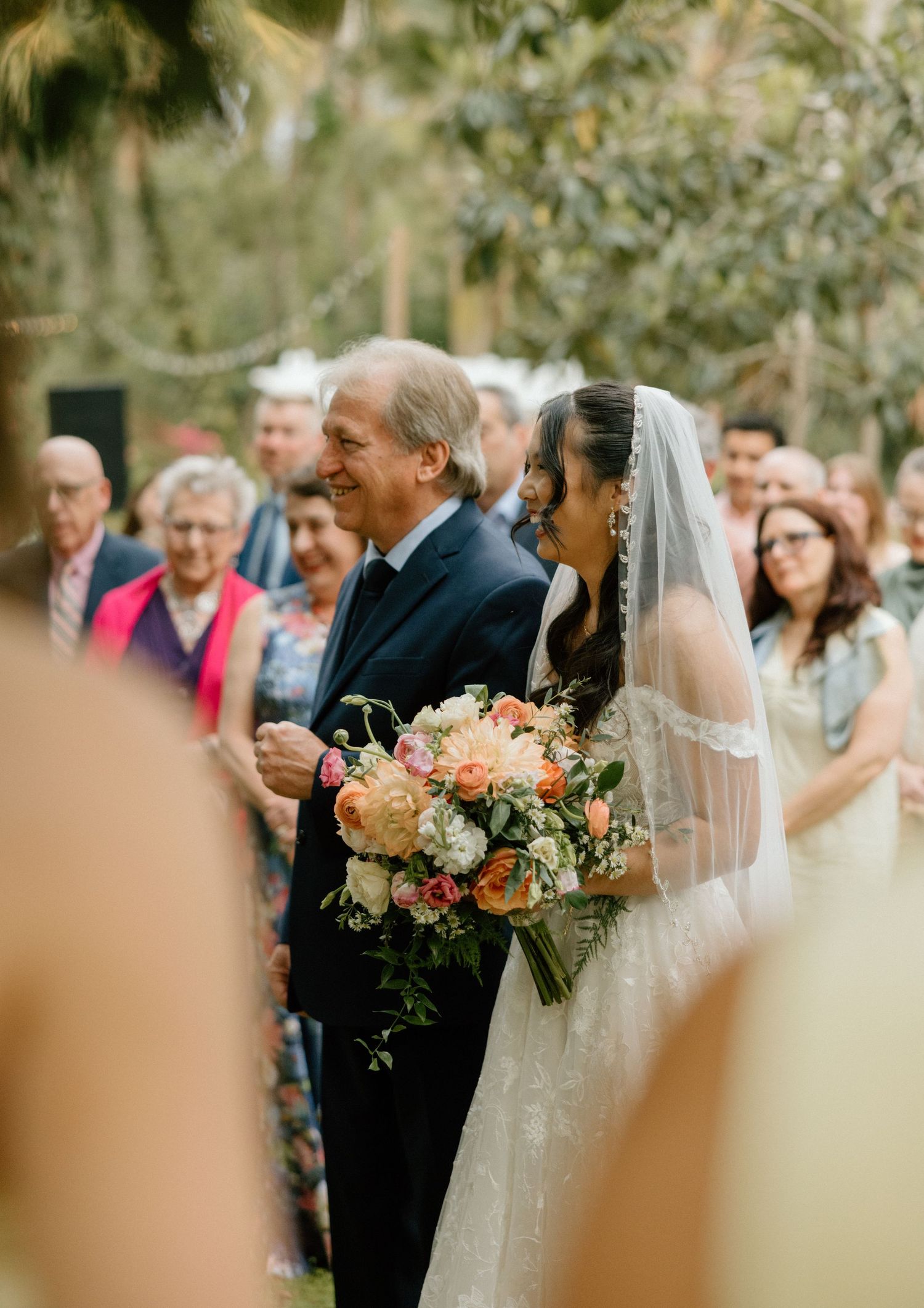 A beautiful outdoor wedding ceremony in a garden setting with guests looking on as the couple shares a tender moment.