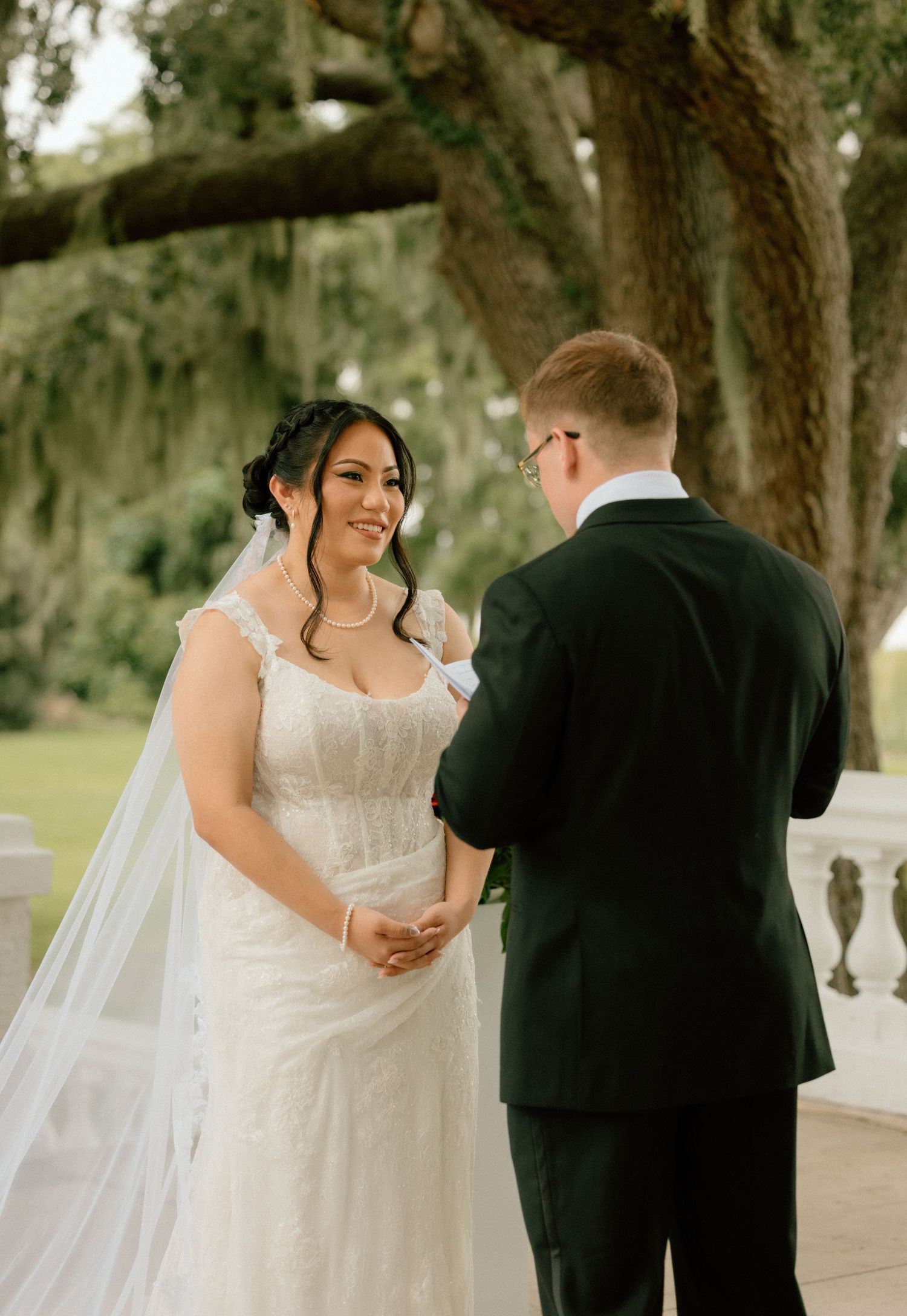 A wedding couple shares an intimate moment under Spanish moss-draped trees during their outdoor ceremony.