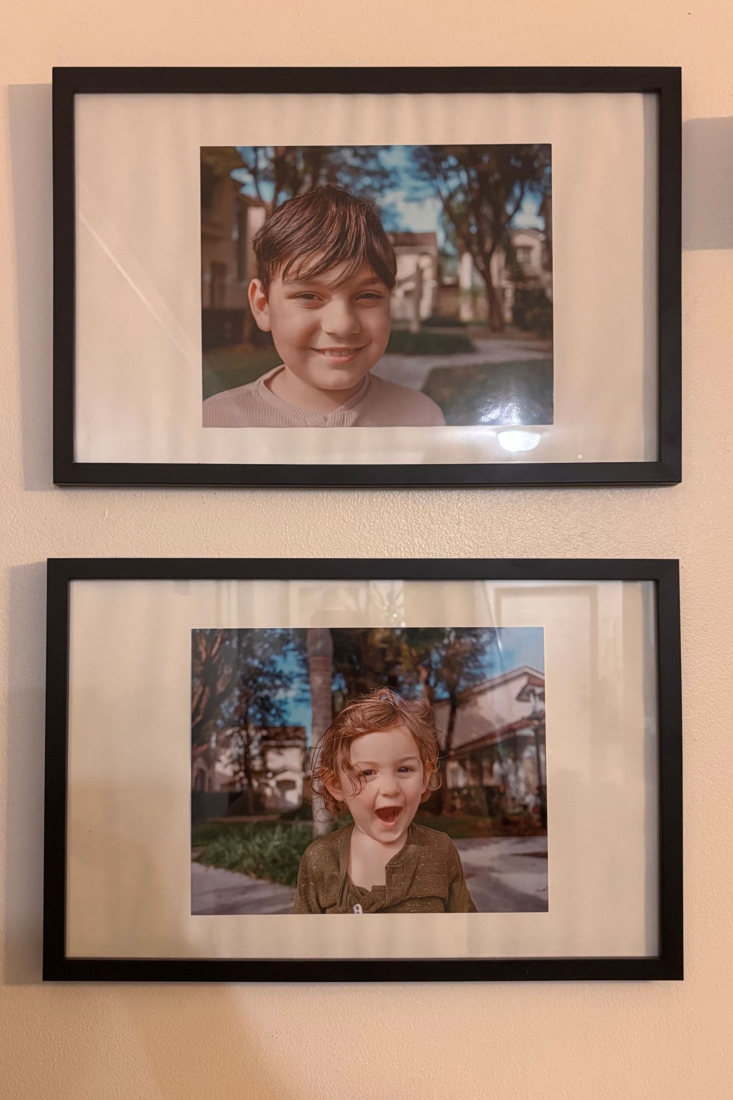 Two framed photographs mounted on a peach-colored wall.