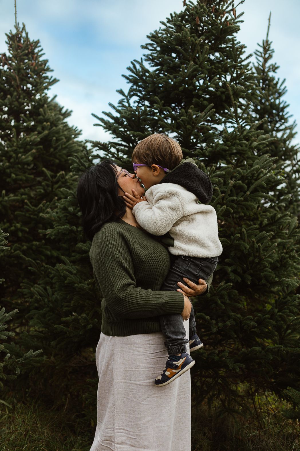 Tender embrace against evergreen trees in a natural outdoor setting.