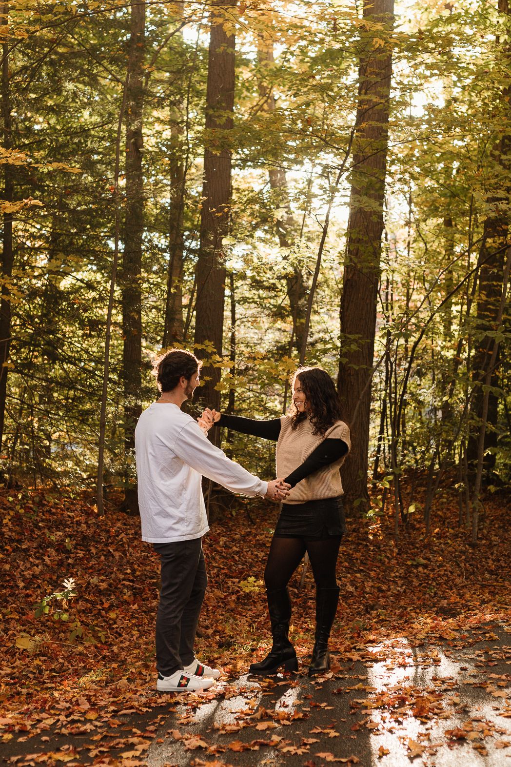 People dancing and spinning in a sunlit autumn forest with golden leaves.