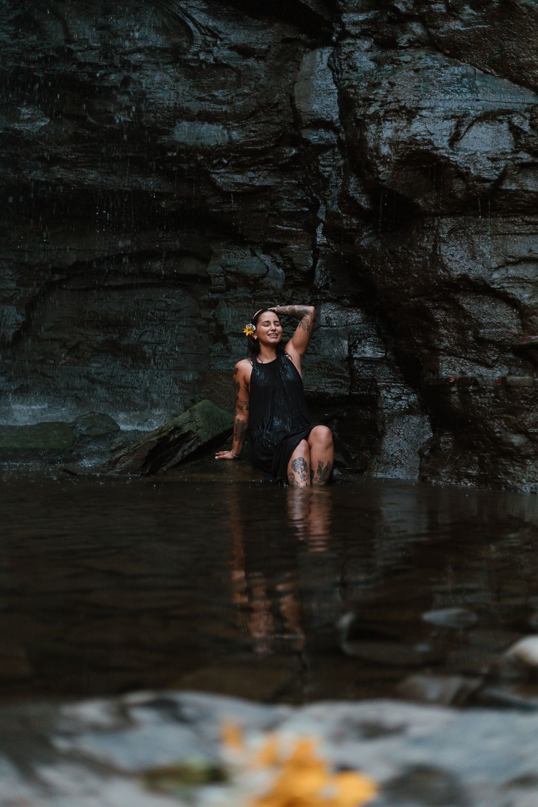 Figure in dark water poses dramatically against rocky cliff wall.