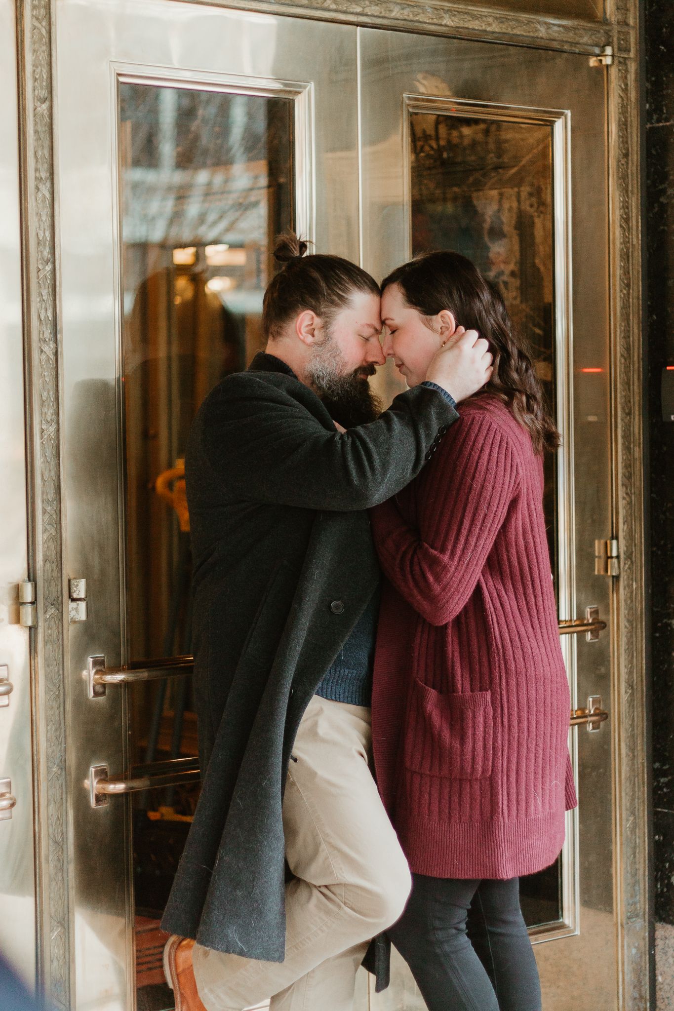 Romantic moment between couple against glass doors.