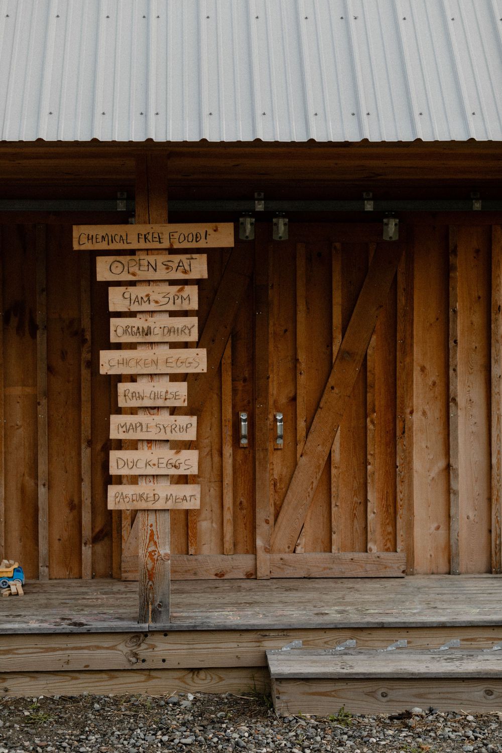 A rustic wooden barn entrance with multiple directional signs mounted on the wall.