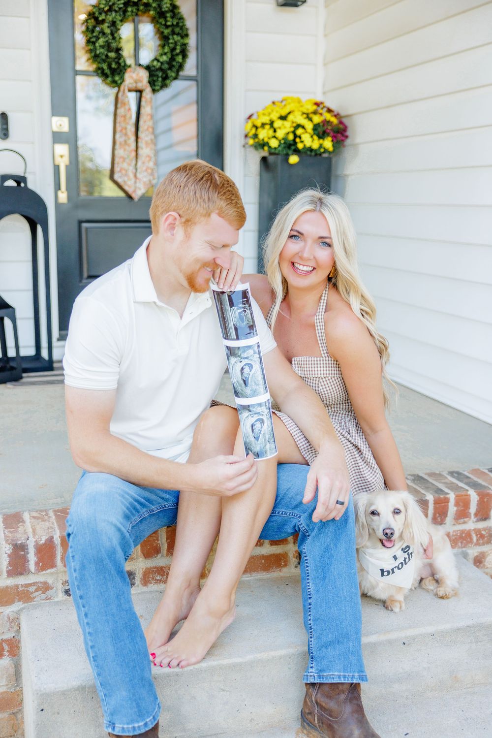 Baby announcement display front porch scene with decorative wreath and small white dog and ultrasound photos.