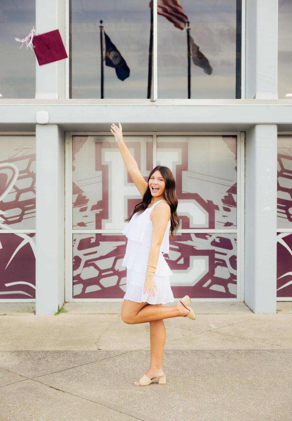 Graduate throwing her graduation cap for senior photos.