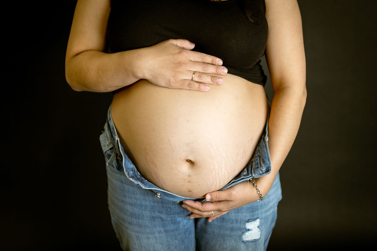 Close-up of a pregnant belly with hands resting on the bump, showcasing the beauty of Oklahoma maternity photography and motherhood.