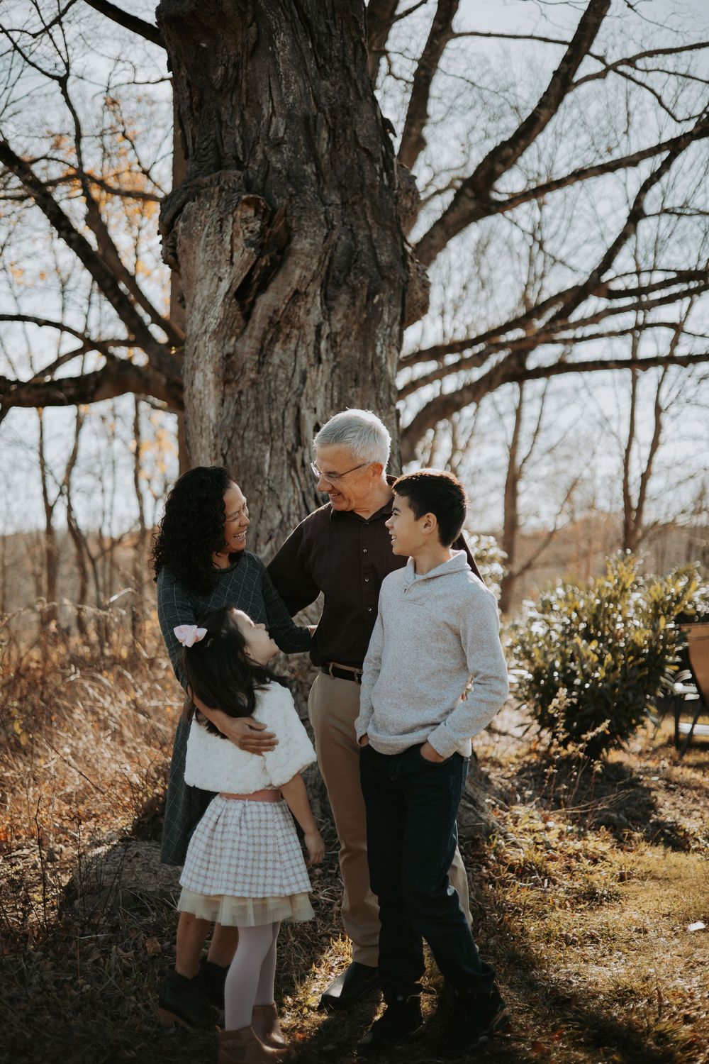 A family shares tender moments together in a wooded outdoor setting during an autumn photoshoot.