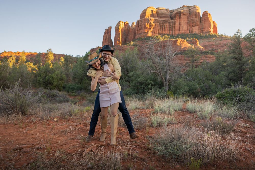 Joyful couple embracing and spinning in Sedona desert landscape at dusk.