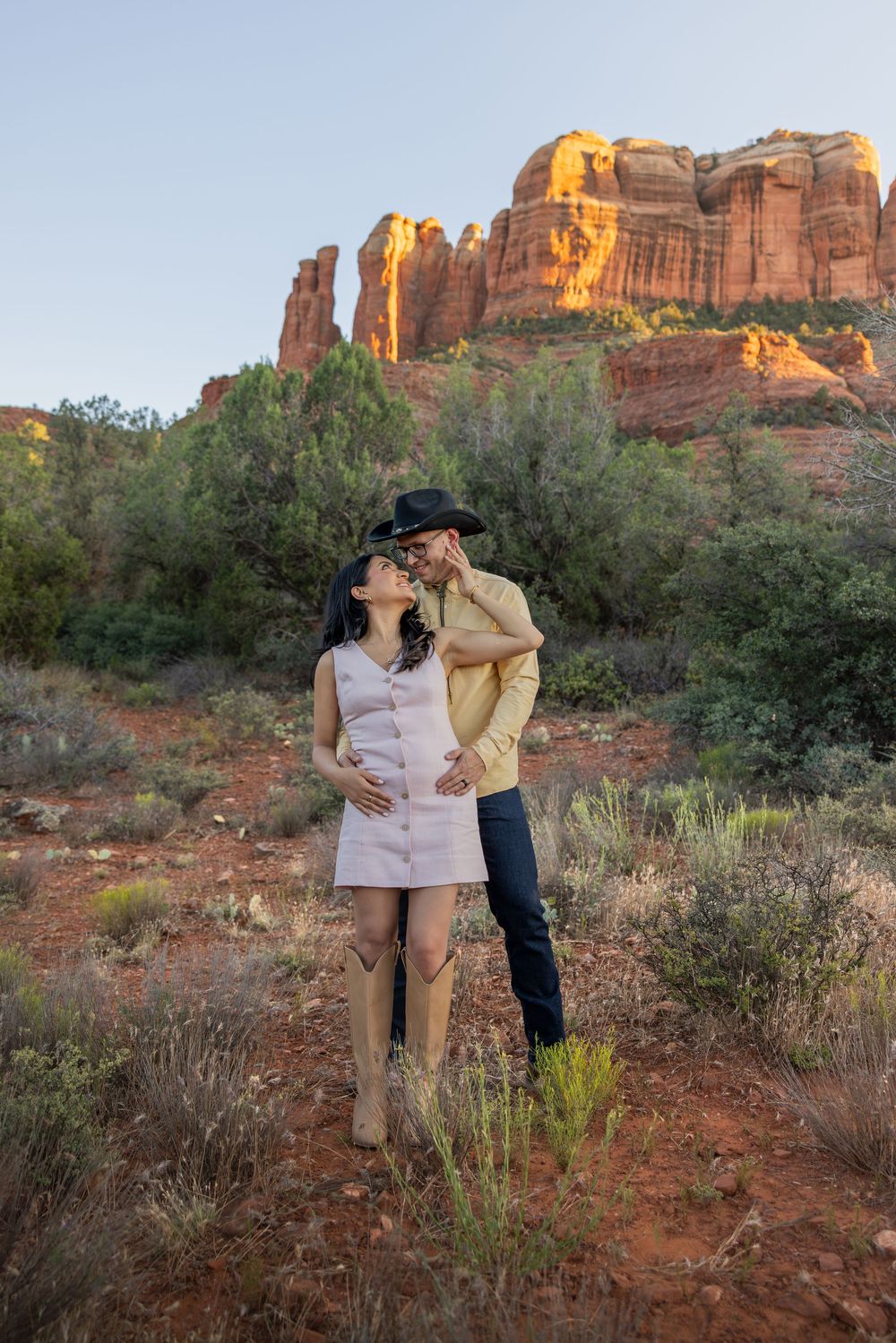 Couple sharing tender kiss near Cathedral Rock in Sedona at sunset.