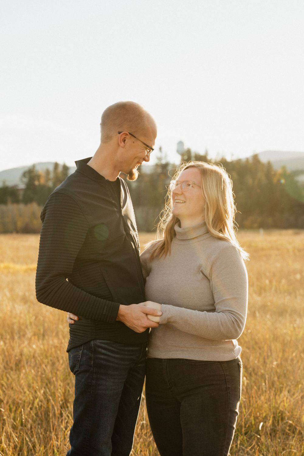 Couple sharing an intimate moment in a golden field at sunset.