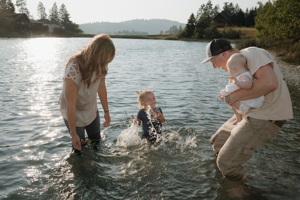 Family plays and splashes together in a mountain lake during golden hour.