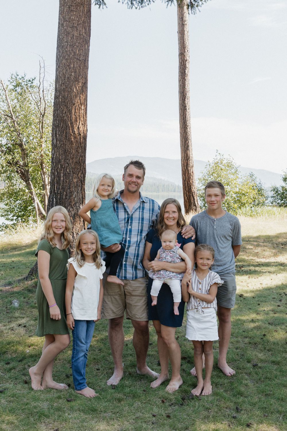 Family portrait of multiple generations standing together outdoors with mountains in background.