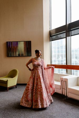 Traditional pink floral lehenga dress photographed in a modern room with large windows and modern furniture.