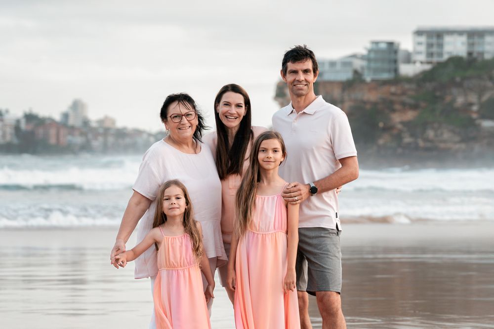 A family hugging each other in front of the ocean in the northern beaches Freshwater while having their family photoshoot
