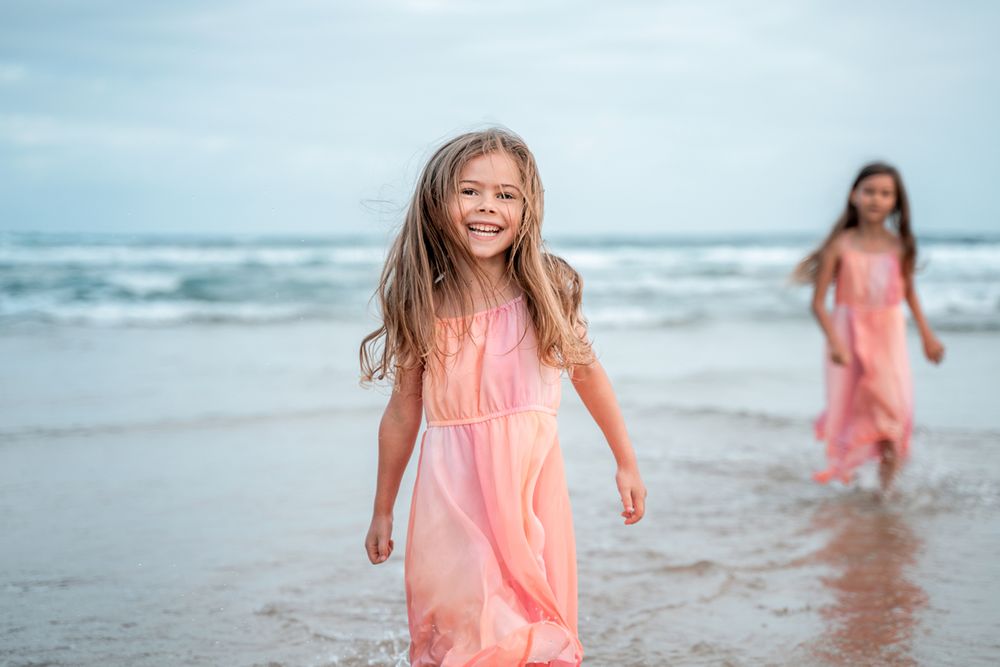 Happy girl jumping in the ocean and getting wet during a family photoshoot in Sydney