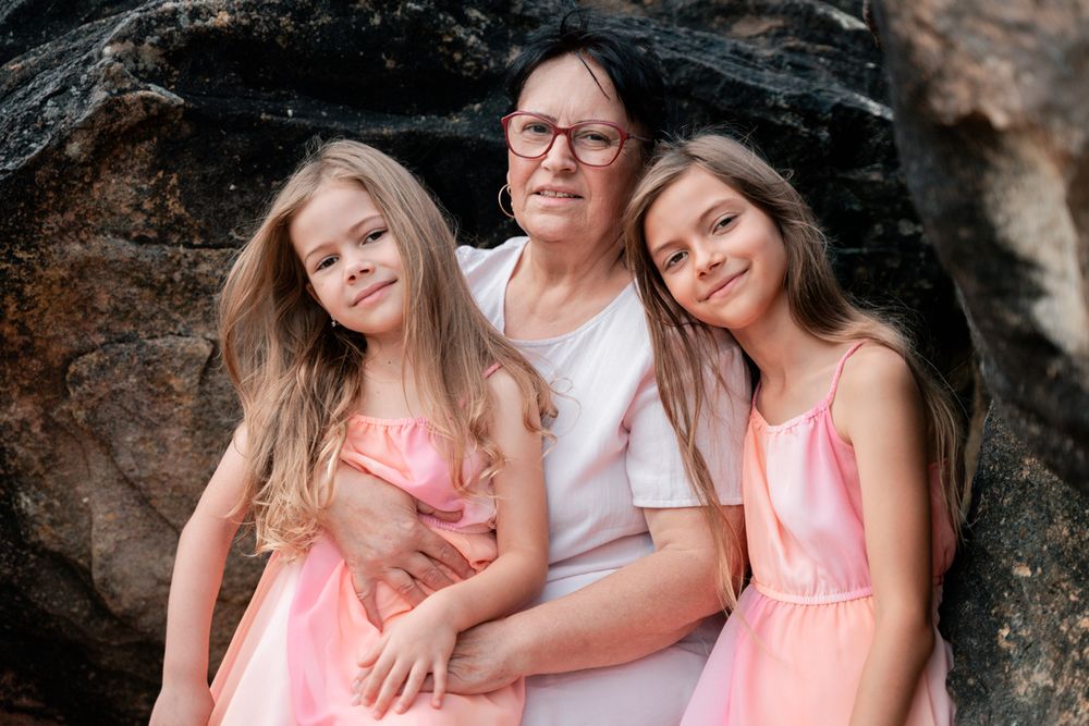 Siblings girls and their grandma sitting on a rock at Freshwater Beach in Sydney during a family photoshoot