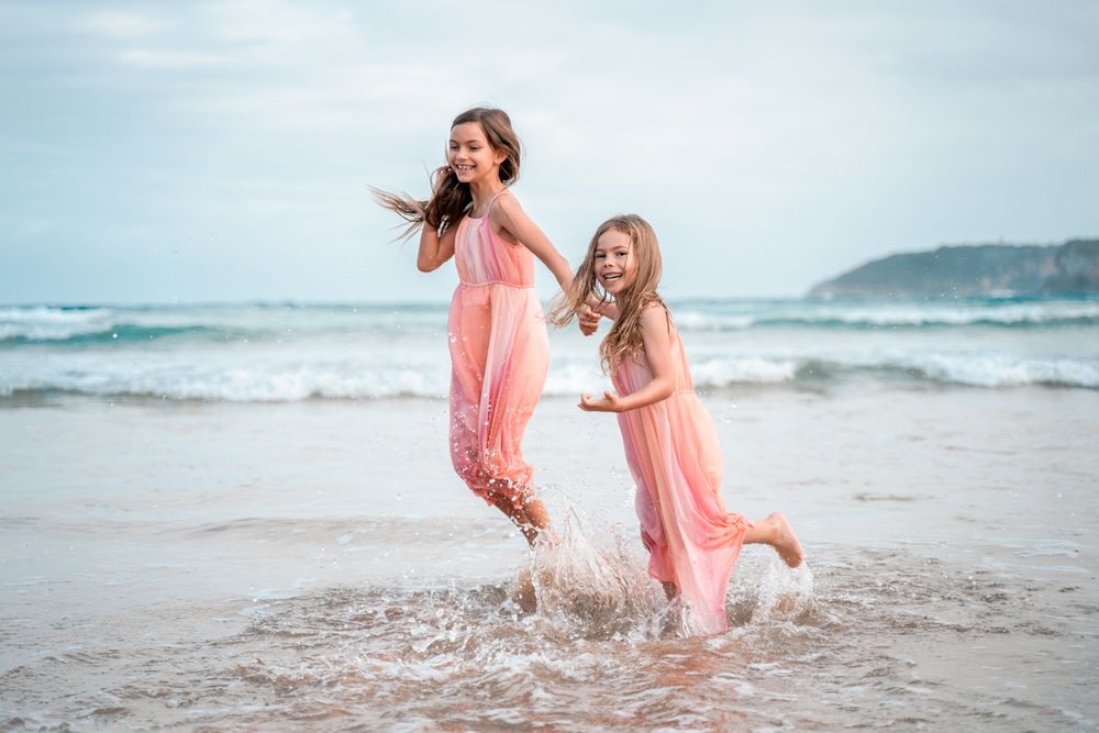 Happy girls jumping in the water at Freshwater beach in Sydney during a family photoshoot
