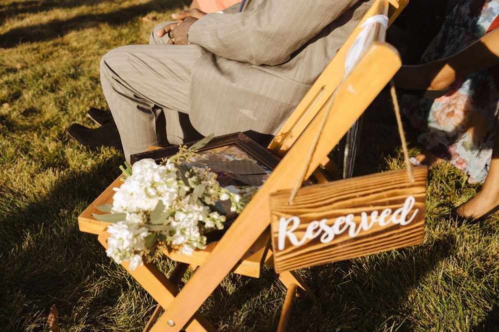 Wooden folding chair with 'Reserved' sign and white floral bouquet sits on grass in golden sunlight near vernon nj.