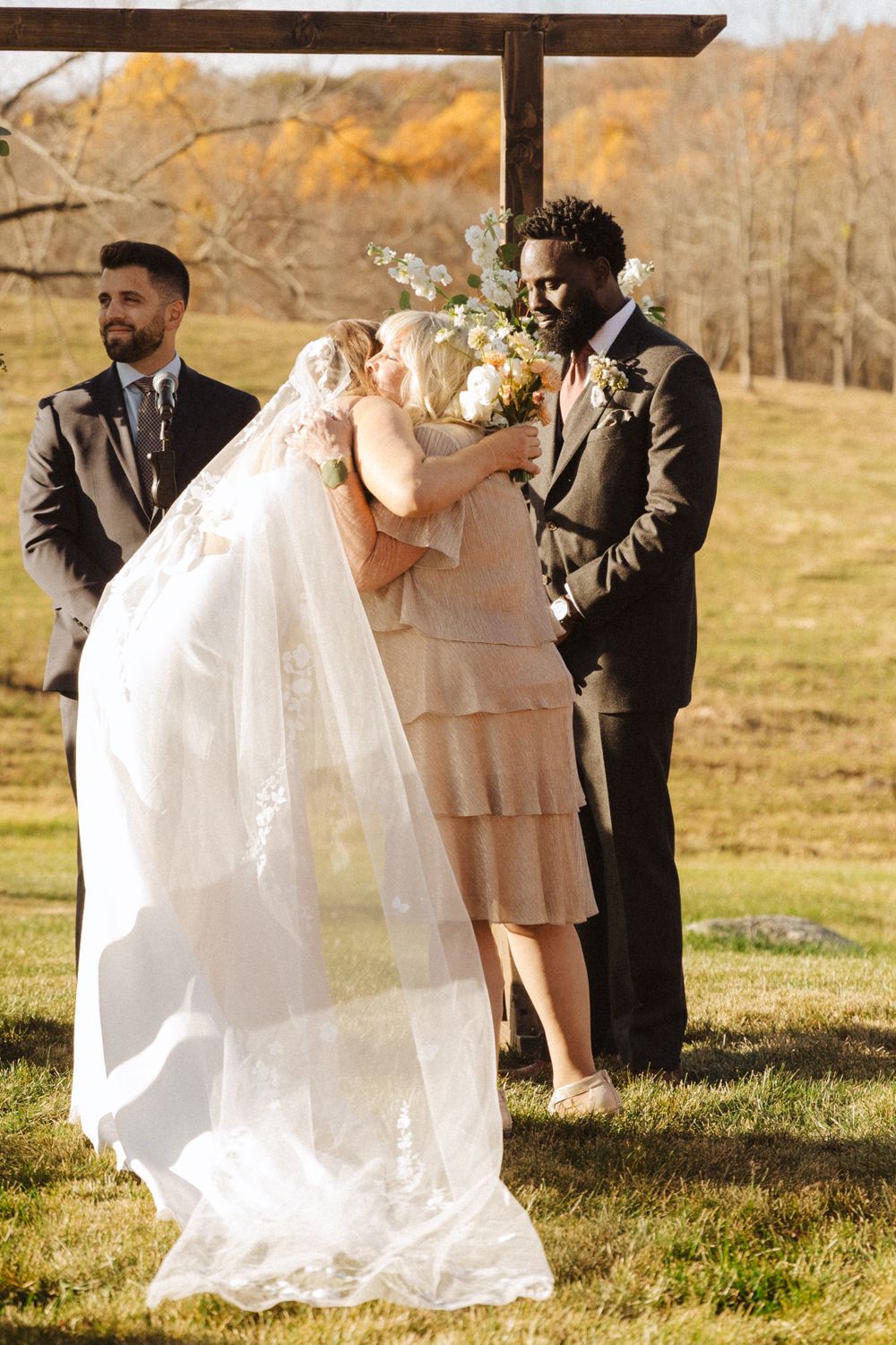A couple exchanges vows during an autumn outdoor wedding ceremony with an officiant in a pink dress near vernon nj.