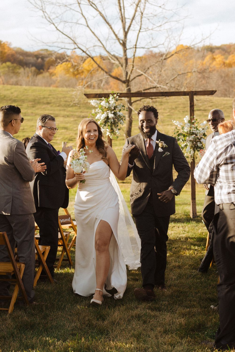 Outdoor rustic autumn wedding ceremony with wooden arch and floral arrangements in a golden field at sunset near vernon nj.