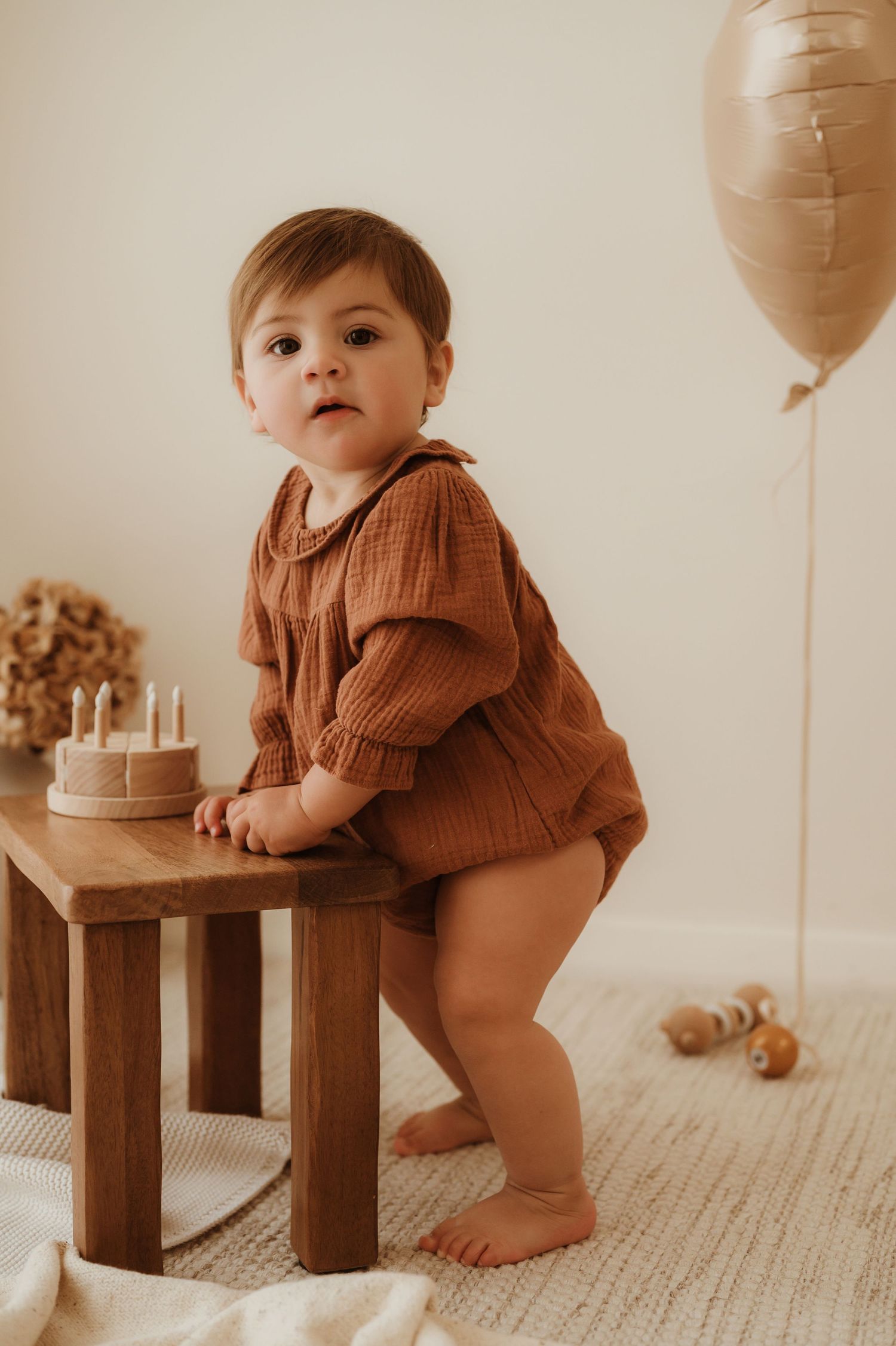 Joyful baby in white clothing laughs while being held in warm indoor lighting.