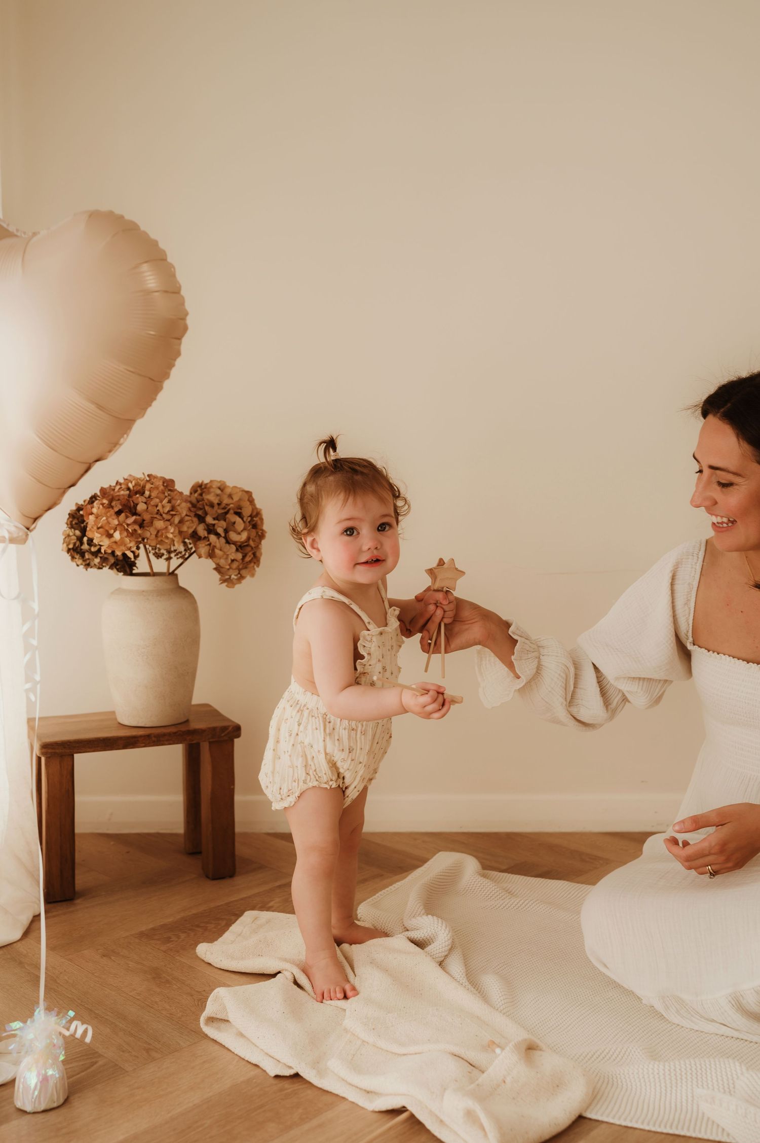 Joyful baby in white clothing laughs while being held in warm indoor lighting.