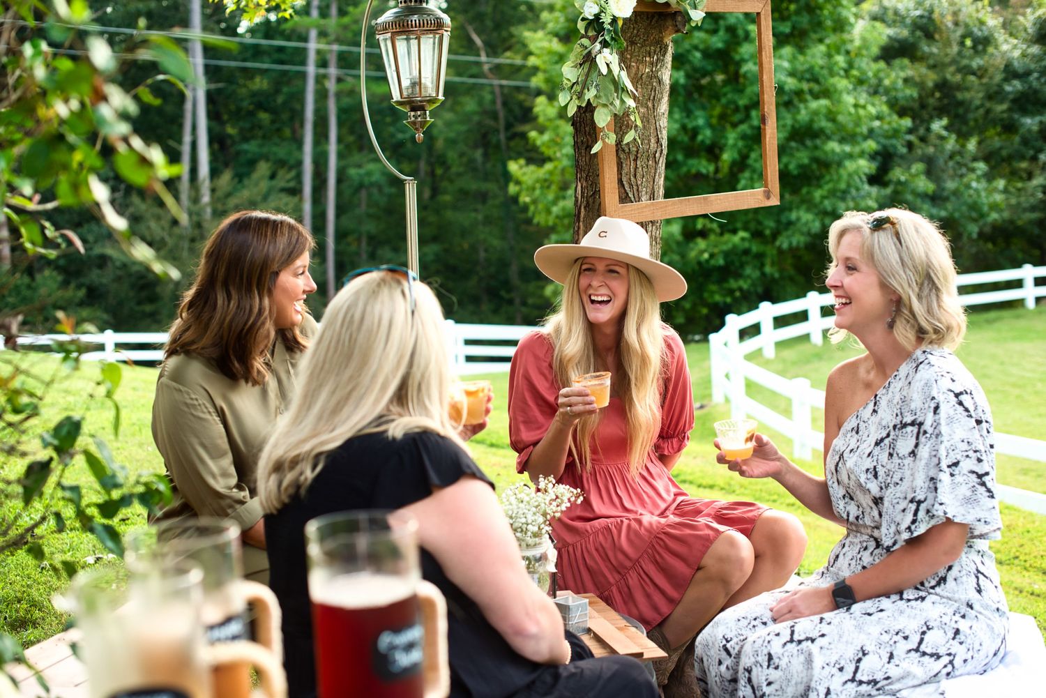 Friends enjoying drinks and conversation at an outdoor garden party under string lights.
