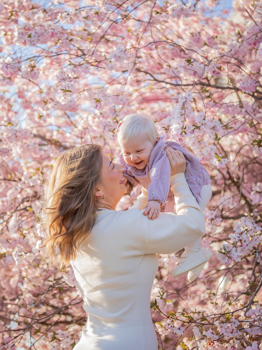 Mamma och barn vid blommande träd i kvällsljus, familjefotografering Västerås. MemoriebyM