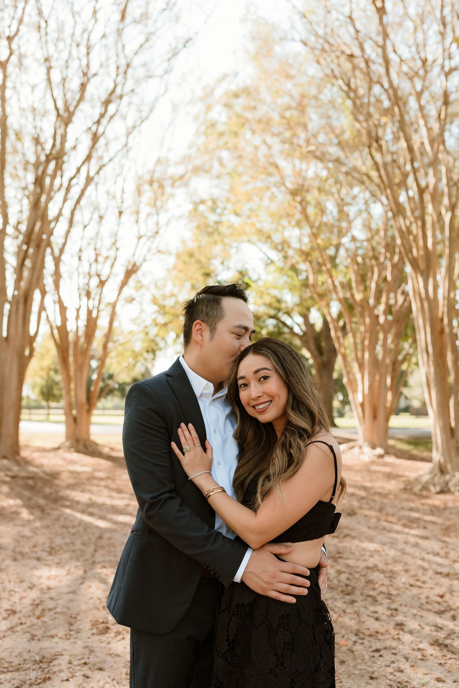 Couple embraces lovingly among autumn trees during outdoor photoshoot.