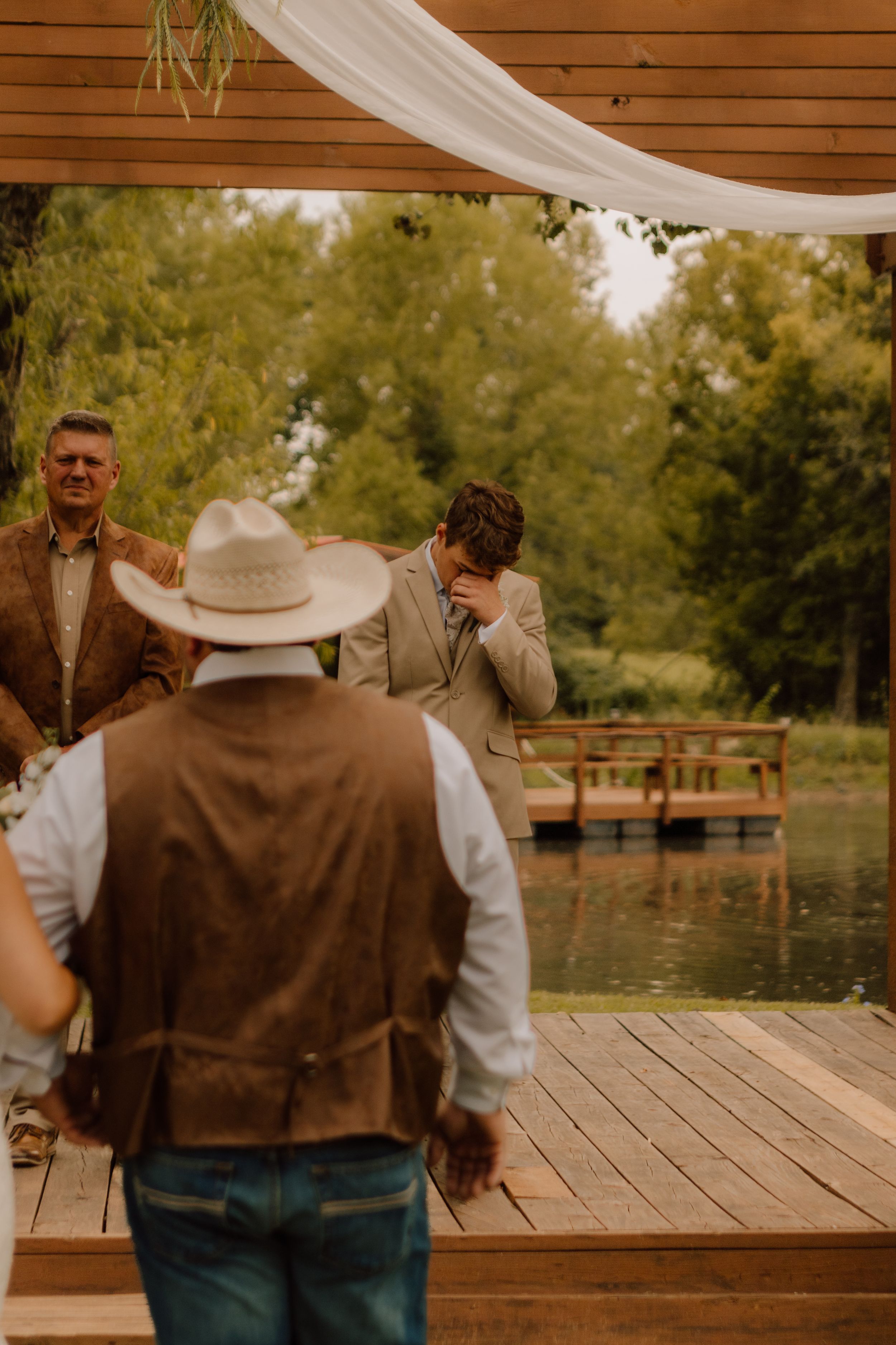 An emotional moment captured during a wedding ceremony on a lakeside deck.