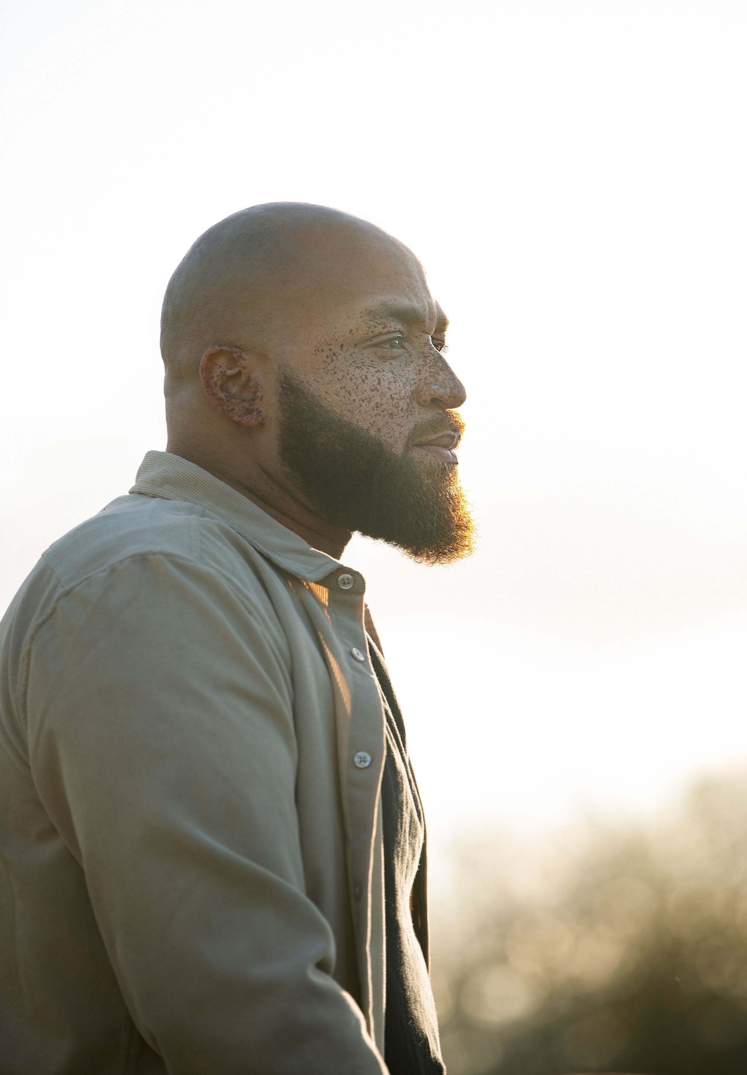 Profile silhouette of man with beard wearing grey jacket in warm sunset lighting.