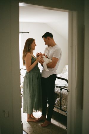 A couple in casual attire stands barefoot in a doorway, sharing an intimate moment together.