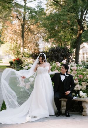 Romantic wedding couple shares intimate moments in a lush garden setting with flowing white dress and veil.