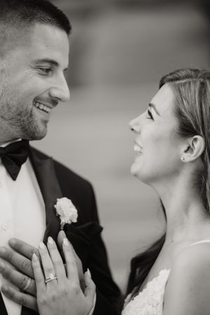 Black and white photo of a wedding couple sharing a joyful moment together as they hold hands.