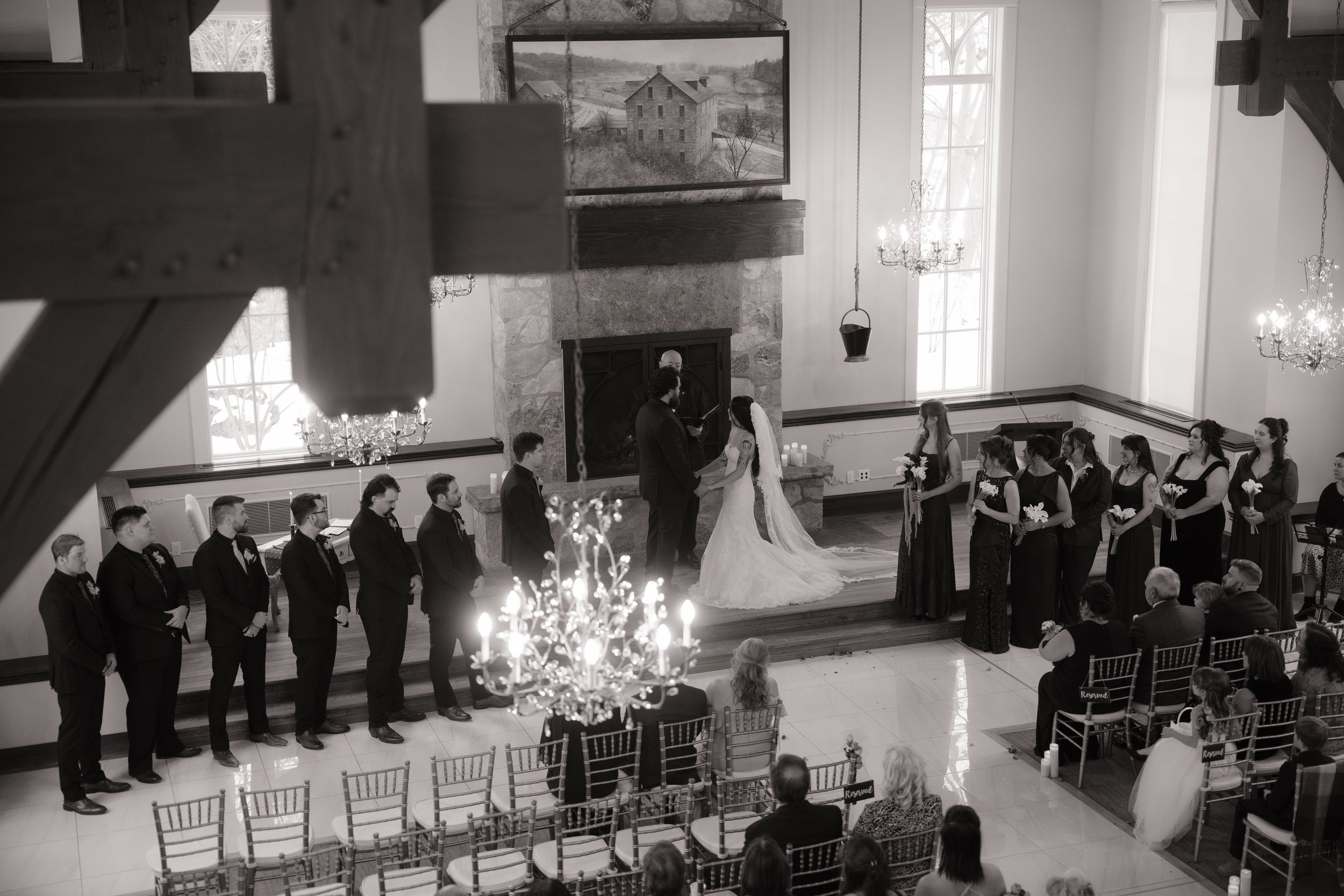 Wedding guests seated in rows of white chairs inside an elegant chapel with natural light streaming through windows.
