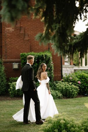 A classic wedding moment captured in a garden setting with red brick walls and lush greenery.