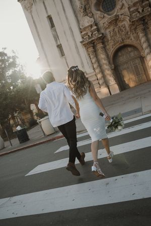 Couple walking together on a paved path next to ornate historic architecture during sunset.