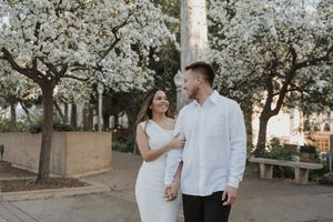 Couple embracing under blooming cherry blossom trees on a spring day.