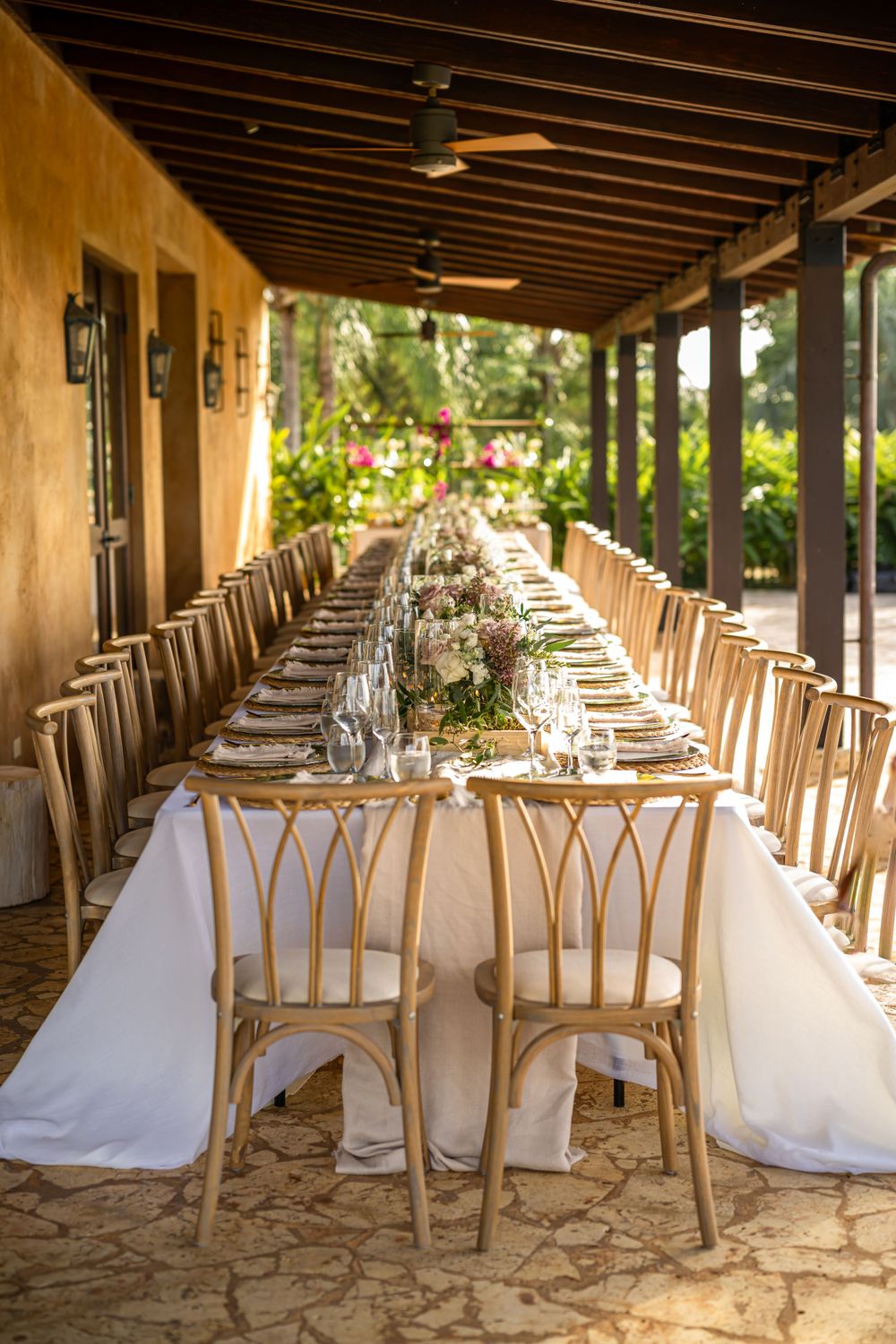 Close-up of luxurious place settings with gold chargers and green plates on white tablecloth.
