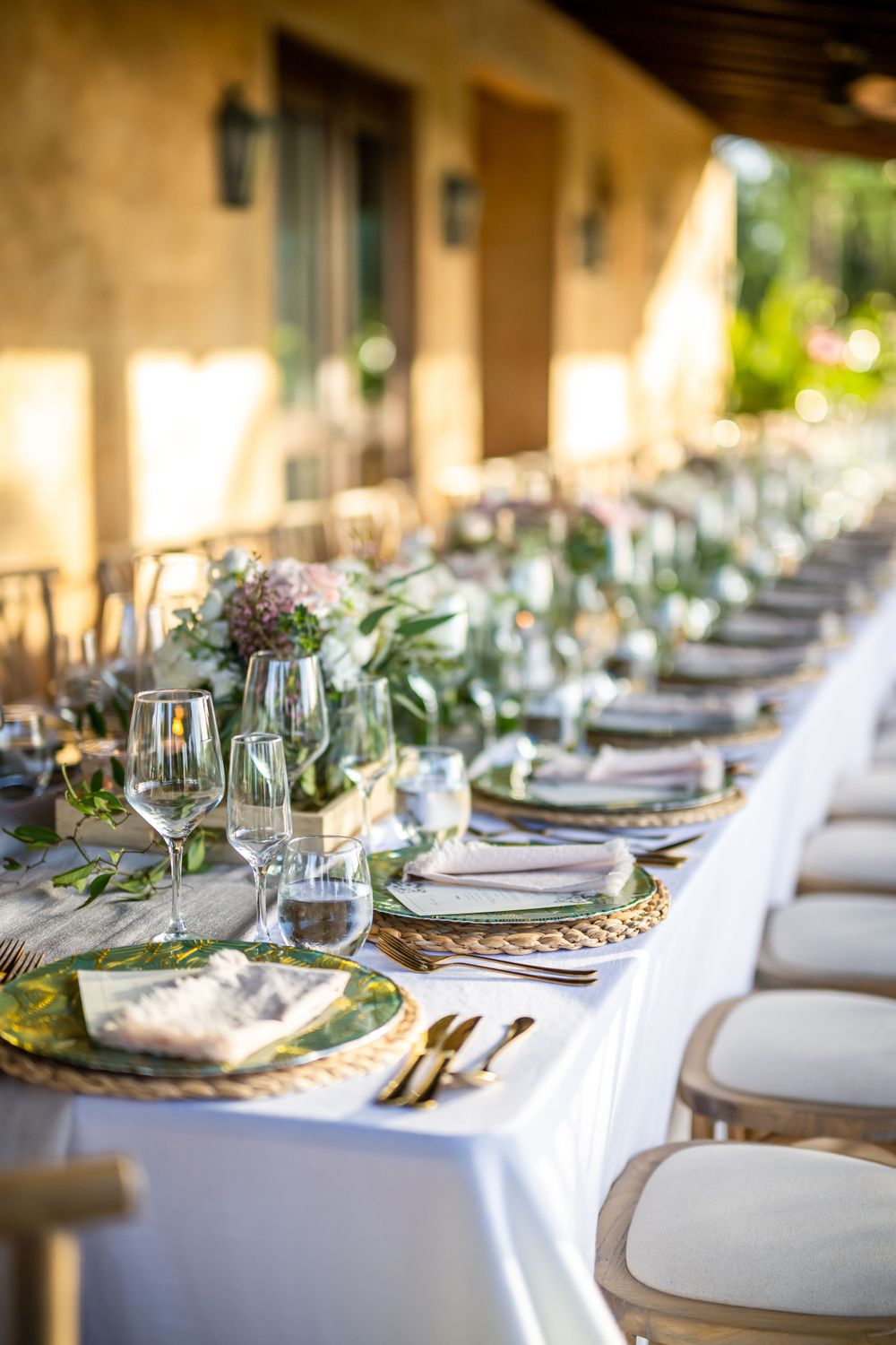 Romantic table setting with pink roses, crystal glasses and gold accents in natural lighting.
