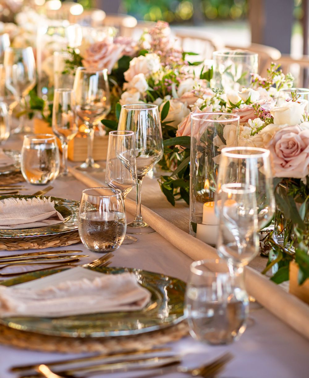 Romantic table setting with pink roses and wine glasses in warm lighting.