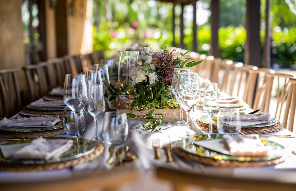 Elegant wedding table setting with floral centerpieces and wine glasses at outdoor reception.
