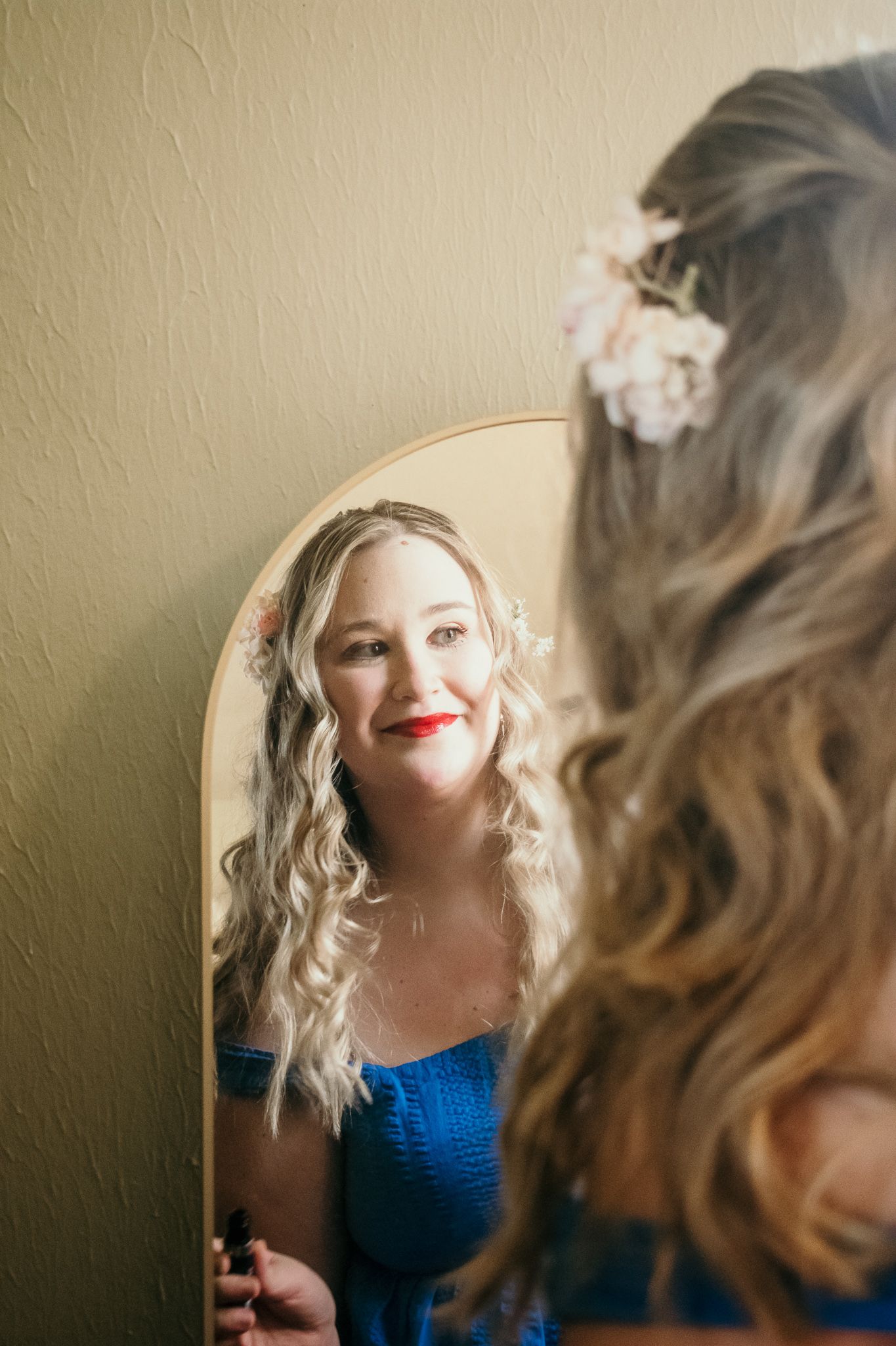Mirror reflection shows elegant hairstyle with floral accessories.