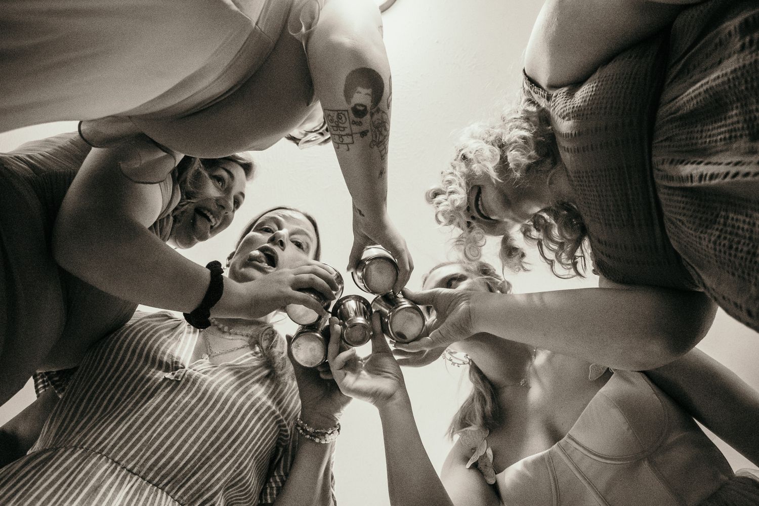 A group cheers with drinks in a circle formation from a low angle perspective.