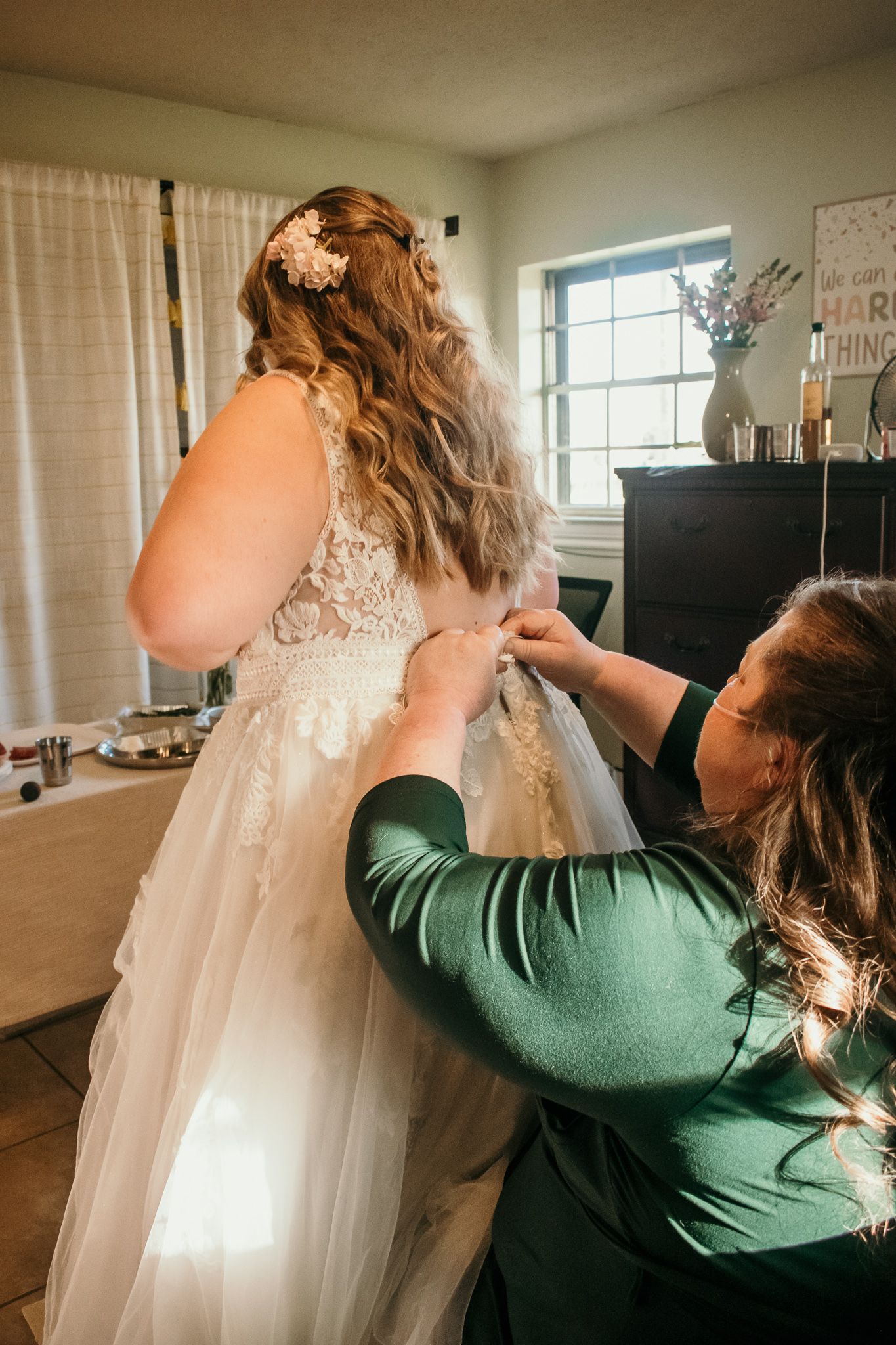 A wedding dress being fastened and adjusted during bridal preparations.