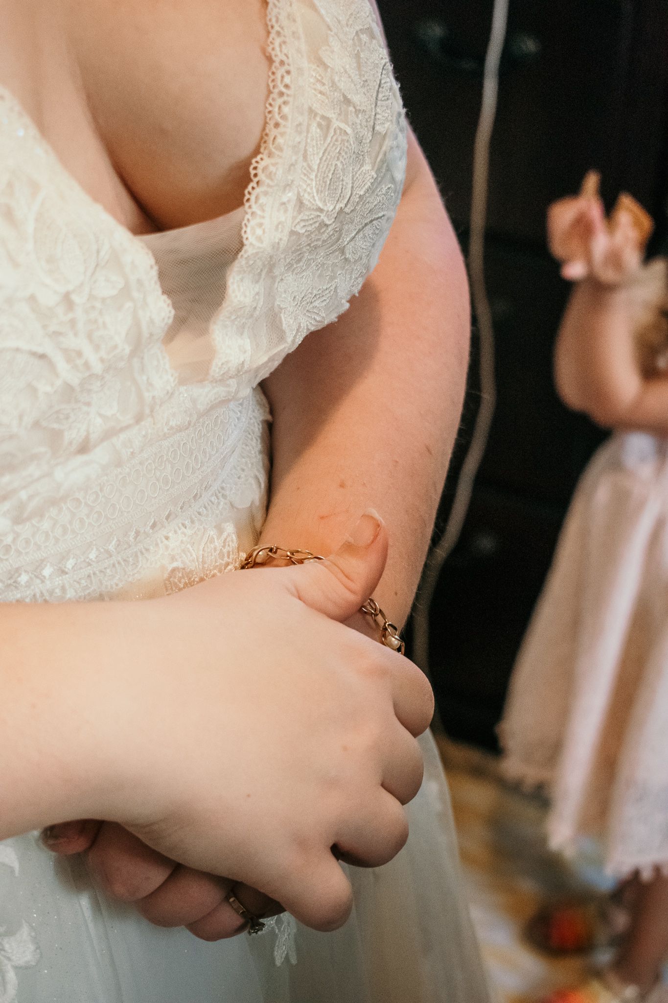 Close-up detail of a wedding dress showing delicate white lace and embroidery details.
