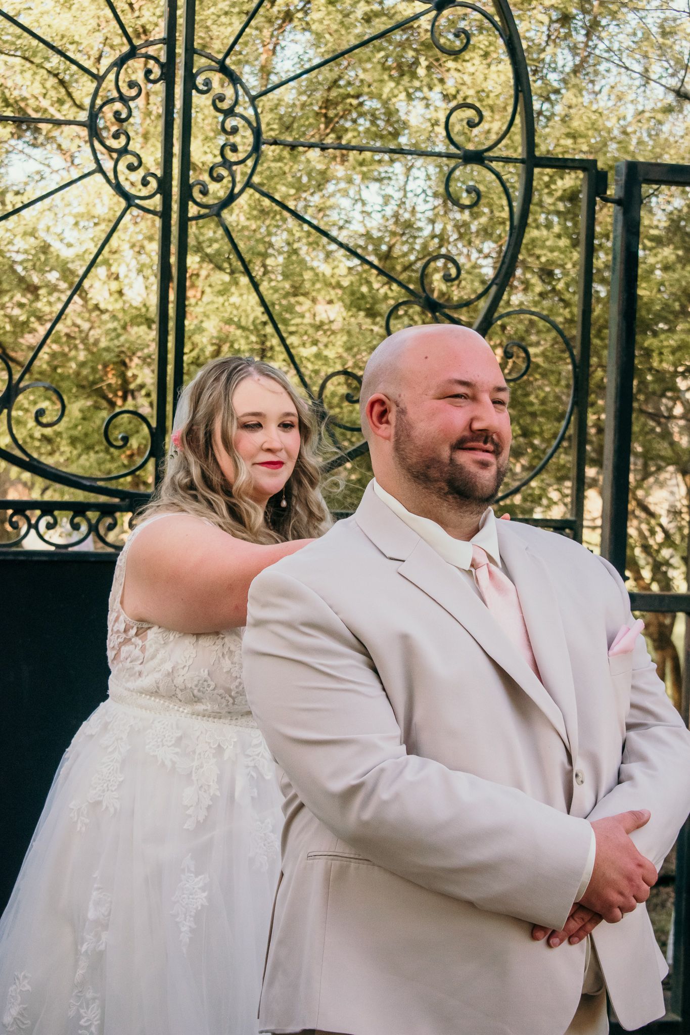 A couple shares a special moment in front of an ornate wrought iron garden gate.